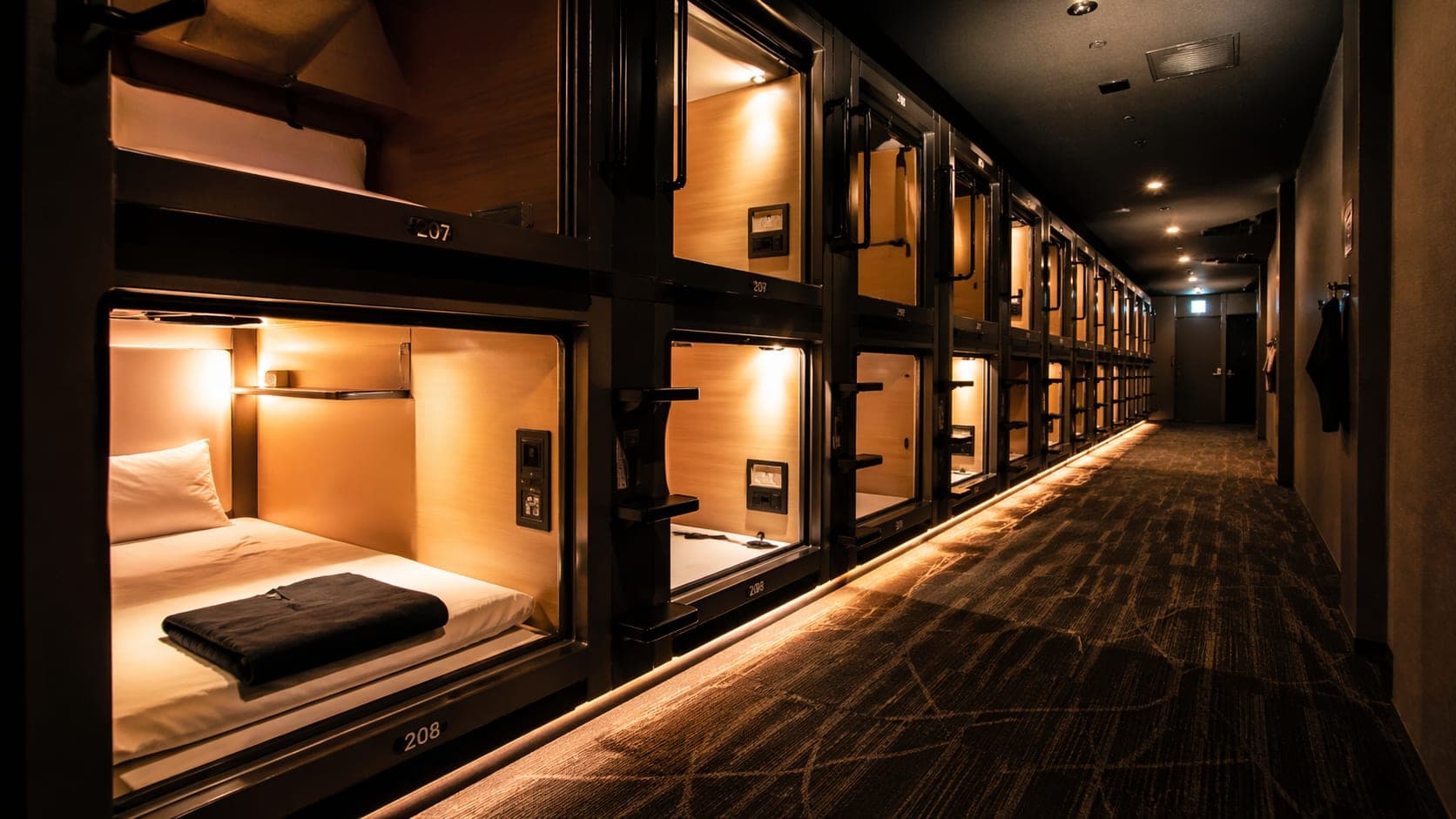 Interior of a capsule hotel in Japan with futuristic sleeping pods and ambient lighting.