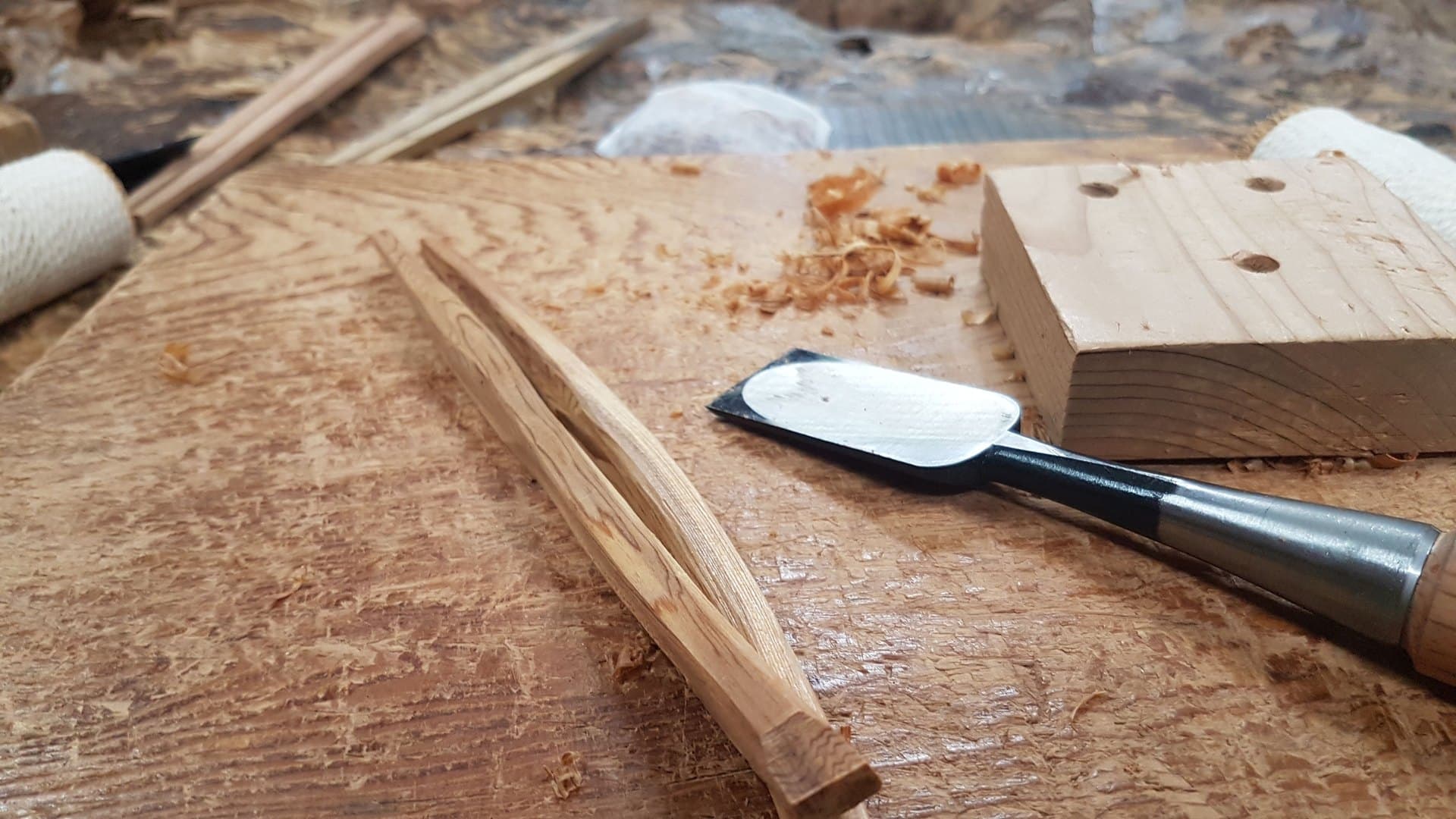 Hand plane, wood shavings and a pair of handmade cedar chopsticks on a workbench